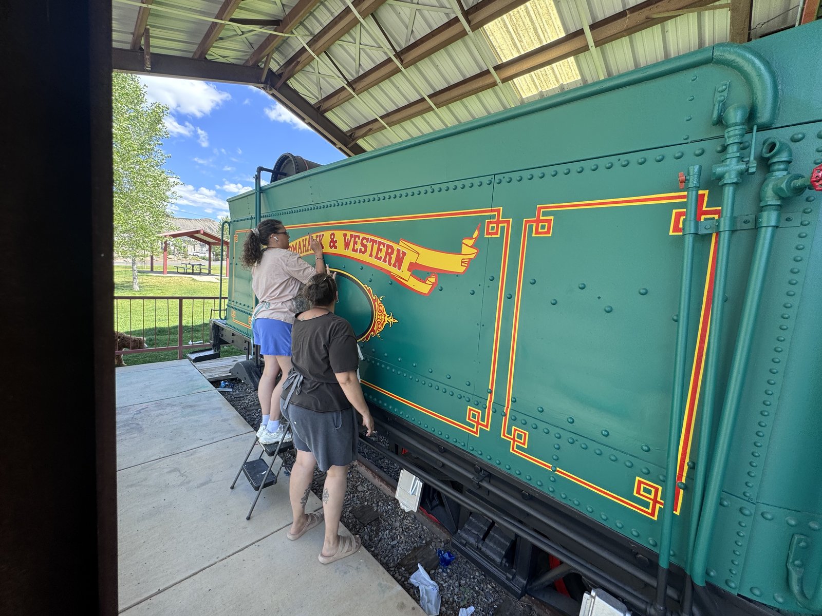 Rocky Top Painting crew hand-lettering Tomahawk and Western tender car — active restoration