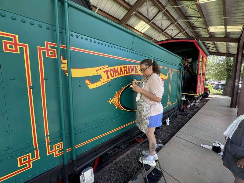 Rocky Top crew painting Tomahawk lettering — historic train restoration Durango CO